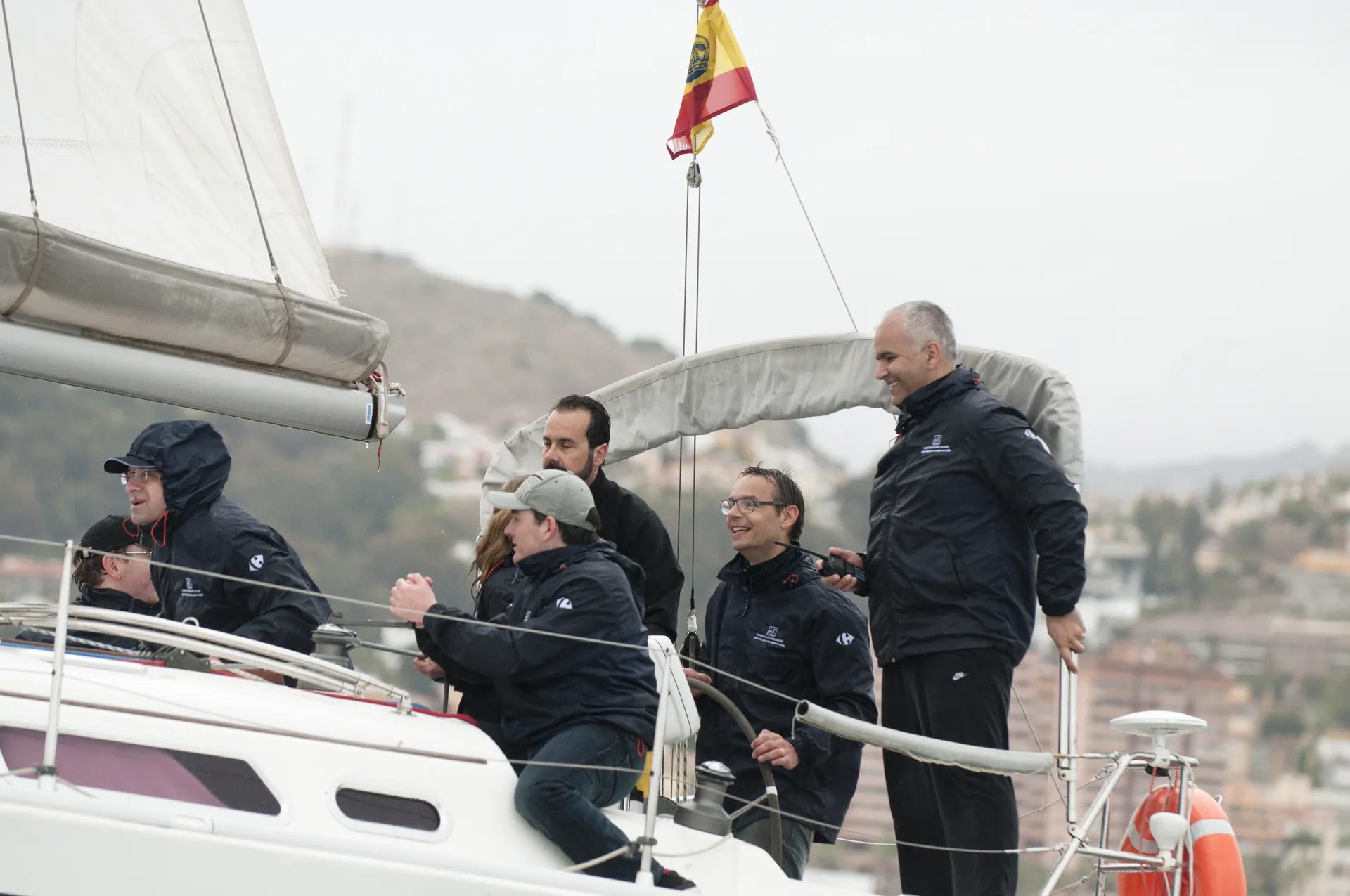 Equipo de managers de Carrefour a bordo del velero, con el puerto de Málaga al fondo.