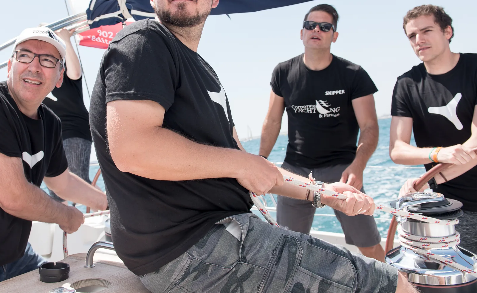 Cuatro participantes trabajando en equipo en la maniobra del velero.