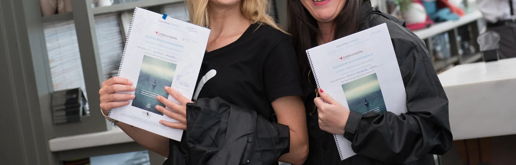 Dos participantes sonrientes con los cuadernos del programa tras una jornada formativa.