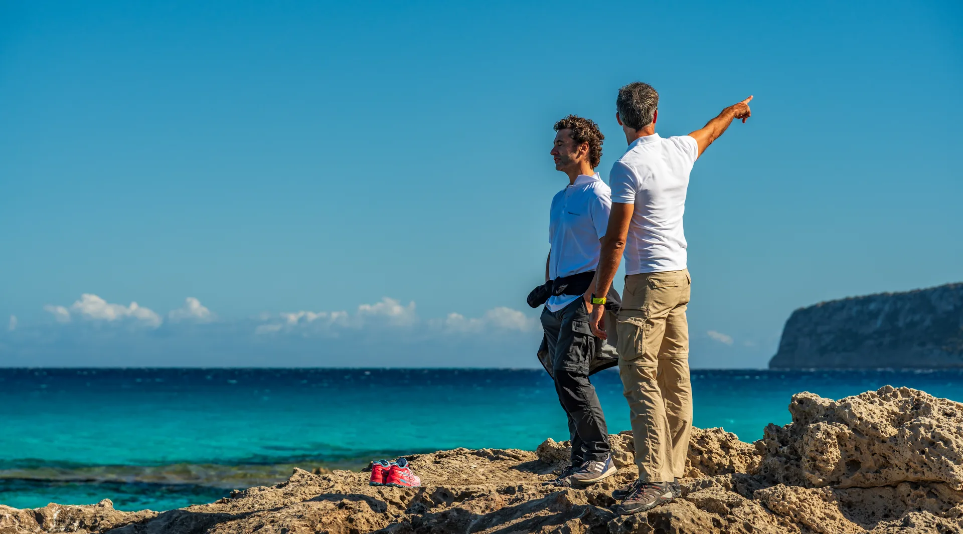Dos participantes observando el horizonte desde un promontorio rocoso sobre el mar.