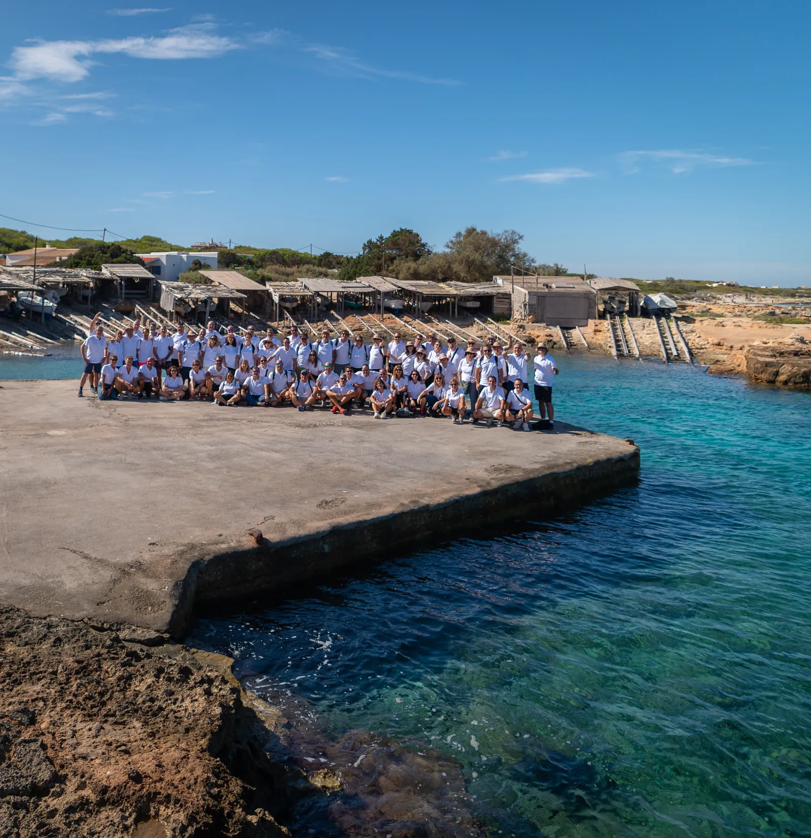 Fotografía de grupo del equipo participante posando sobre el espigón, junto a la cala.