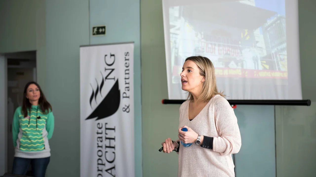 Ponente exponiendo una charla con una imagen proyectada de fondo, ante el público