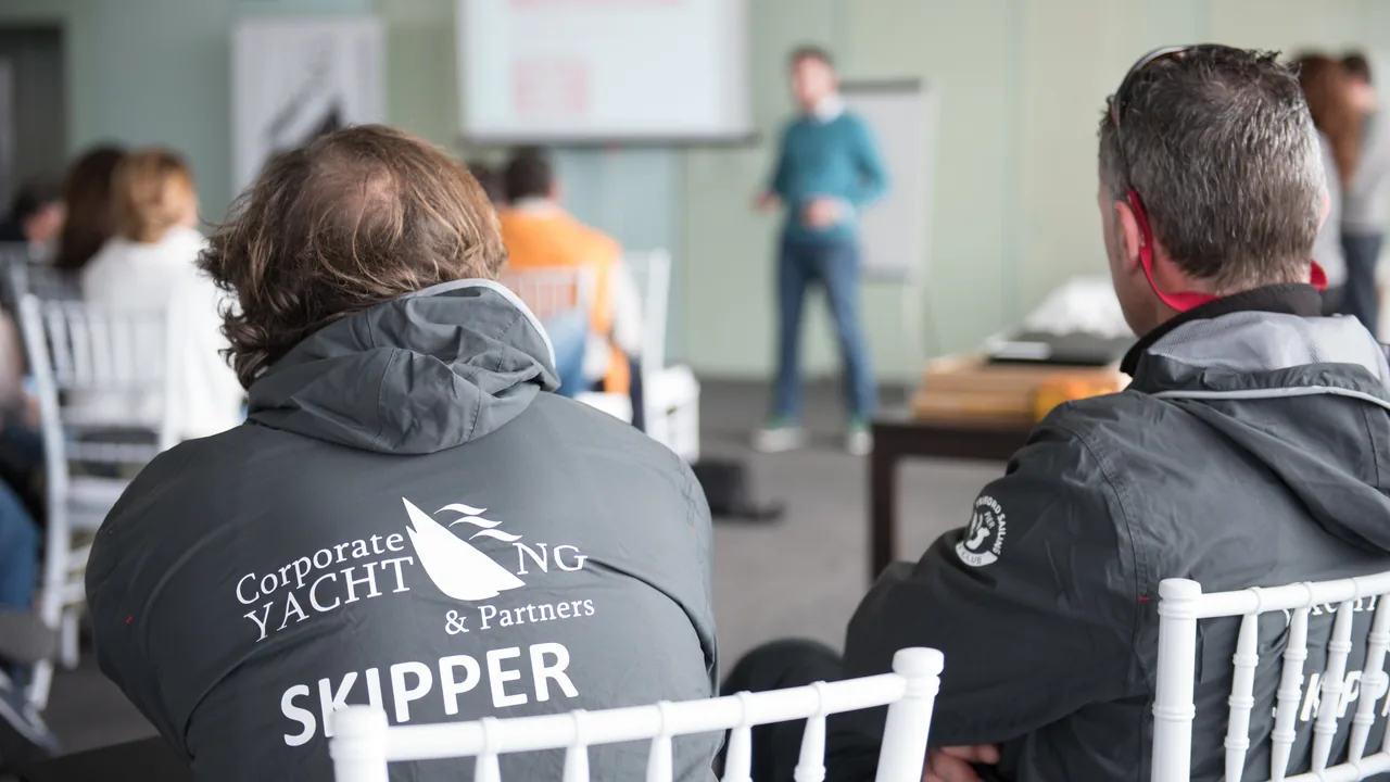 Participantes con chaqueta de 'Skipper' siguiendo una presentación con papelógrafo al fondo